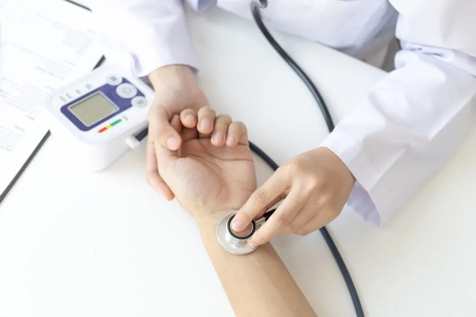 Checking pulse using stethoscope over wrist.